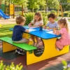 Stolik piknikowy dla dzieci z niebieskim blatem, dwiema zielonymi ławkami i żółtą konstrukcją